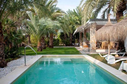 a swimming pool in front of a house with palm trees at Villa Bonita en Alicante. in Elche