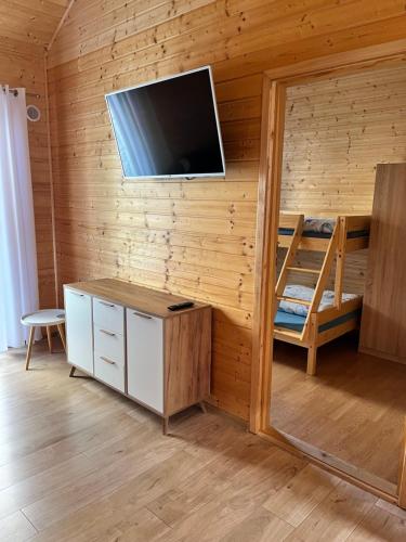 a room with a bunk bed and a tv on a wall at Domki Kapitan Antonio in Ustronie Morskie