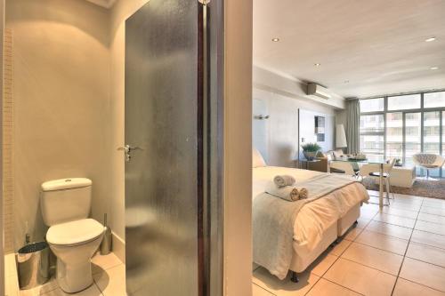 a bedroom with a bed and a bathroom with a toilet at The Icon Studio Apartment 1000 in Cape Town