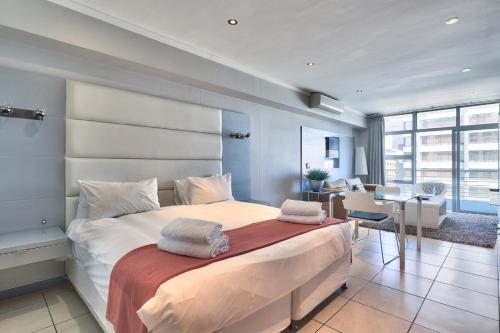 a bedroom with a large bed with two towels on it at The Icon Studio Apartment 1000 in Cape Town
