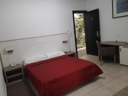 a bedroom with a red bed and a table and a desk at Residence ACHENBACH in Abidjan