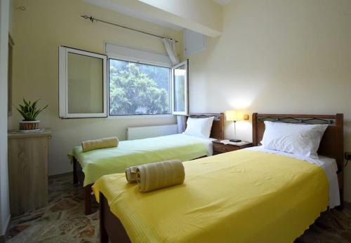 a room with two beds with yellow sheets and a window at Villa Eirini Agia Varvara Lesvos in Plomarion