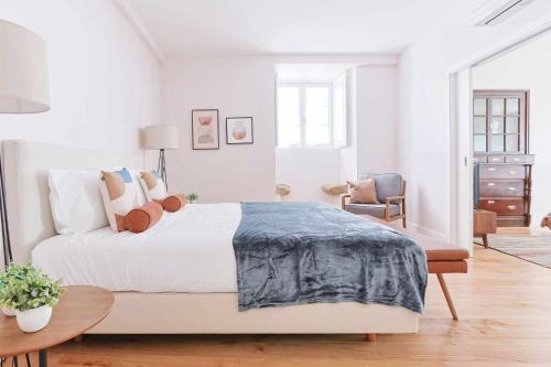 Un dormitorio blanco con una cama grande y una silla. en Downtown Charming Apartments Apartamento Poldras, en Chaves