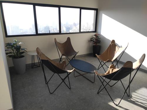 un gruppo di sedie e un tavolo in una stanza con finestre di Studio de cobertura perto da av. Paulista a San Paolo