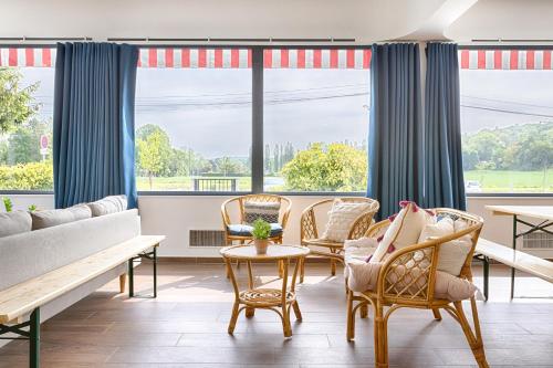 - un salon avec des chaises, un canapé et des fenêtres dans l'établissement La Coudraie - Proche de Disneyland, à Montévrain