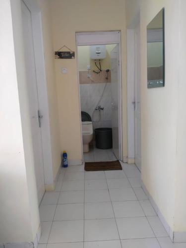 a bathroom with a toilet and a white tile floor at Villa Highland No 7 M Berastagi View in Berastagi