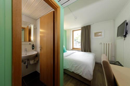 a bathroom with a bed and a sink in a room at Hôtel de l'Ange in Nyon
