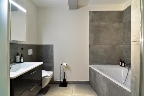 ein Badezimmer mit einer Badewanne, einem WC und einem Waschbecken in der Unterkunft SAXX Apartments Leipzig in Leipzig