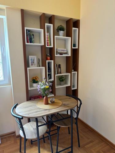 a table and chairs in a room with a book shelf at Suncani apartman 36, Brzece in Brzeće