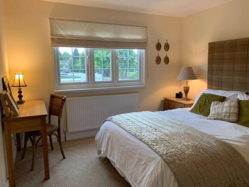 1 dormitorio con cama, escritorio y ventana en 3 Bedroom House with Parking and Garden, en Windsor
