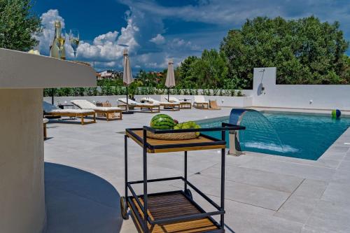 a basket of fruit on a cart next to a swimming pool at Luxury Villa Del Sogno with pool, jacuzzi, parking in Trogir