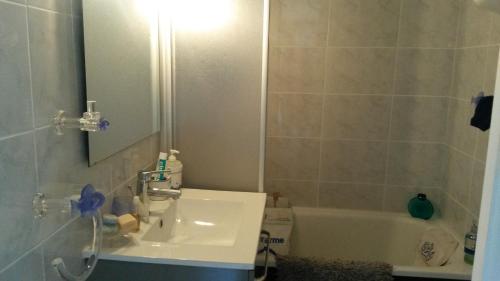 une salle de bain avec un lavabo, une baignoire et un miroir dans l'établissement la plage location a la semaine samedi au samedi, à Villers-sur-Mer