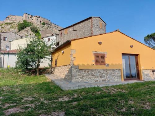 a yellow house with a hill in the background at Casa Fonte in Roccastrada