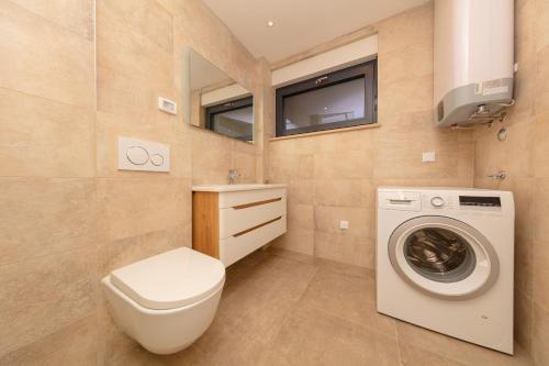 a bathroom with a toilet and a washing machine at Apartman SeaSide 8 in Banjole
