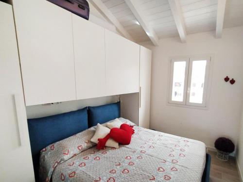 um urso de peluche vermelho sentado em cima de uma cama em Affittimoderni Castelsardo Smeralda CSSM16 em Castelsardo