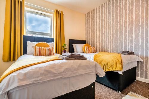 two beds in a bedroom with yellow curtains at Finest Retreats - George Street in Grantham