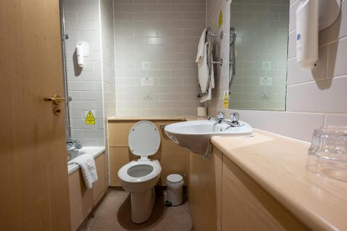 uma casa de banho com um WC, um lavatório e um espelho. em The Fernhurst by Greene King Inns em Blackburn