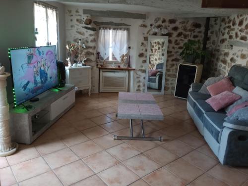 a living room with a couch and a tv at Maison de village in Sourribes