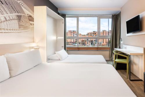 una camera d'albergo con due letti e una finestra di B&B HOTEL Valencia Ciudad de las Ciencias a Valencia