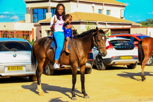 a woman is riding a horse with a child on it at Tlokweng Rose Garden Guesthouse in Gaborone