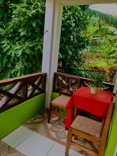 a red table and two chairs on a balcony at Le Petit Paradis in Roseau