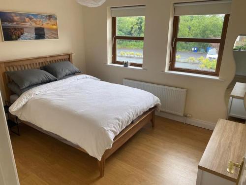 um quarto com uma cama grande e 2 janelas em Beautiful 3 Bedroom House in Coolaney Village County Sligo 