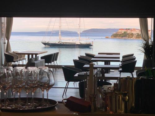 un restaurante con mesas y sillas y un barco en el agua en Hotel Split, en Podstrana