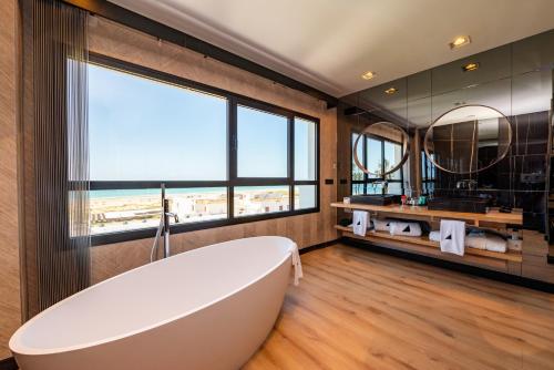 a bathroom with a large tub and a large window at Hotel Antonio II in Zahara de los Atunes