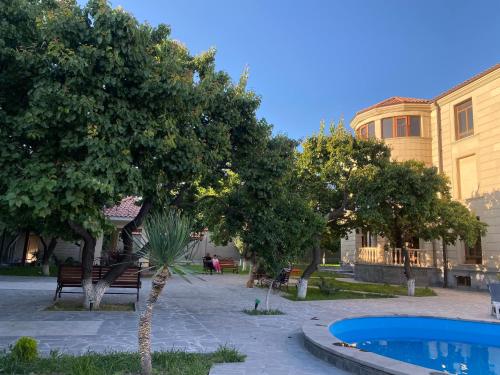 un patio con árboles, una piscina y un edificio en WaterFall Hotel en Ereván