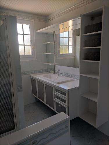 une salle de bain blanche avec un lavabo et un miroir dans l'établissement Maison avec piscine privée, proche plage, à Avrillé