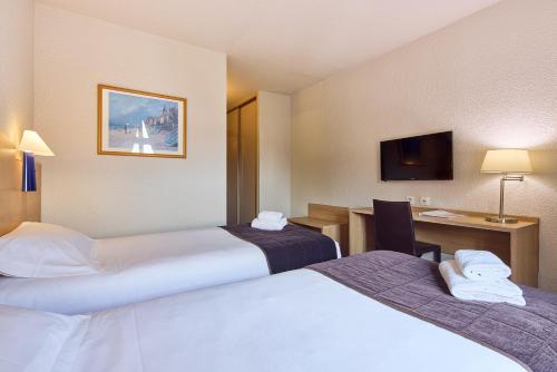 a hotel room with two beds and a desk at Hôtel Saint Laurent in Nogent-sur-Seine