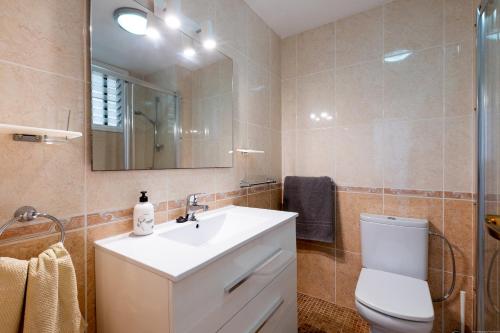 een badkamer met een wastafel, een toilet en een spiegel bij Apartmento Cactus II in Los Cristianos