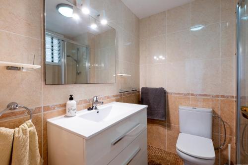 Un baño con lavabo, inodoro y espejo. en Apartmento Cactus II, en Los Cristianos