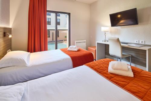 a hotel room with two beds and a desk at Hôtel Saint Laurent in Nogent-sur-Seine