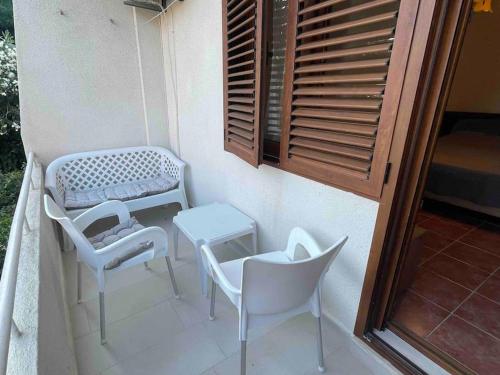 a balcony with white chairs and a table and a window at Comfortable apartment of 50 square meters in Herceg-Novi