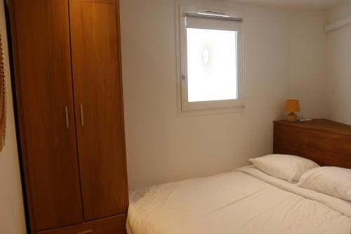 ein kleines Schlafzimmer mit einem Bett und einem Fenster in der Unterkunft Le petit Sud in Carqueiranne