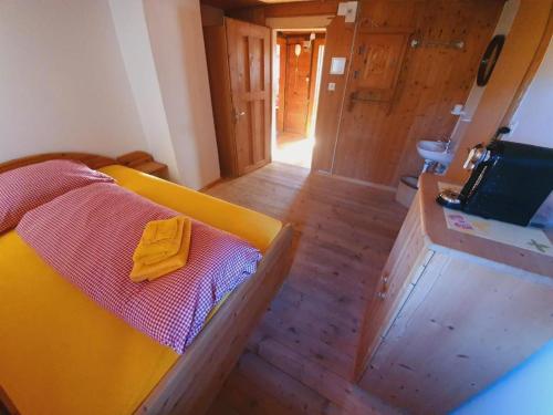 a room with a yellow bed and a wooden floor at Berg-Pension Battagliahütte in Churwalden