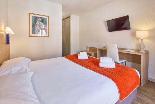 a hotel room with a large white bed and a desk at Hôtel Saint Laurent in Nogent-sur-Seine