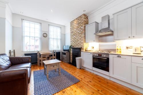 a kitchen with white cabinets and a living room at Stylish 1 BDR apt wcommunal garden, Greenwich in London