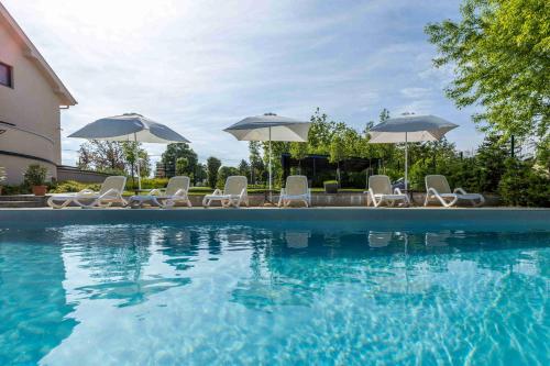 a swimming pool with chairs and umbrellas at Kistücsök Food & Room in Balatonszemes