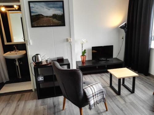 - un salon avec une chaise et une table dans l'établissement Bed & Breakfast Carpe Diem Zeeland, à Serooskerke