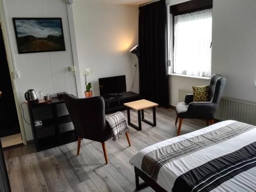 Cette chambre comprend un lit, un bureau et des chaises. dans l'établissement Bed & Breakfast Carpe Diem Zeeland, à Serooskerke