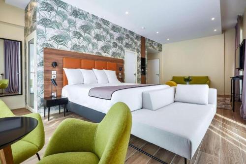 a bedroom with a large bed and two chairs at Quality Hotel Bordeaux Centre in Bordeaux