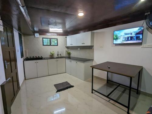 a kitchen with a table and a tv on the wall at Budget Home in Cochin