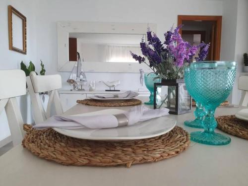 una mesa con un plato y un jarrón con flores púrpuras en Casa con gran jardín y unas preciosas vistas, en Teià