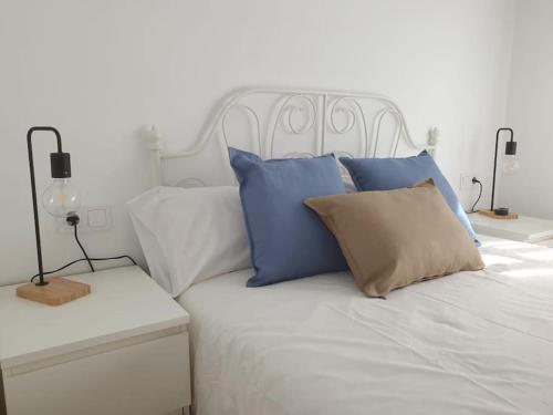 Una cama blanca con almohadas azules y blancas. en Casa con gran jardín y unas preciosas vistas, en Teià