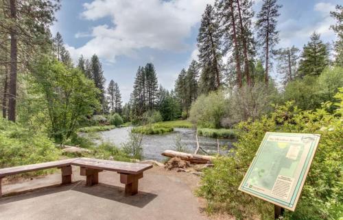 a picnic table and a sign next to a river at Metolius Cabin 4 in Camp Sherman