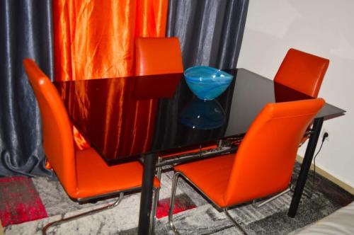 uma mesa com duas cadeiras laranja e um computador portátil em Résidence Lotus em Cotonou