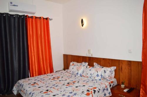 een slaapkamer met een bed met een oranje gordijn bij Résidence Lotus in Cotonou