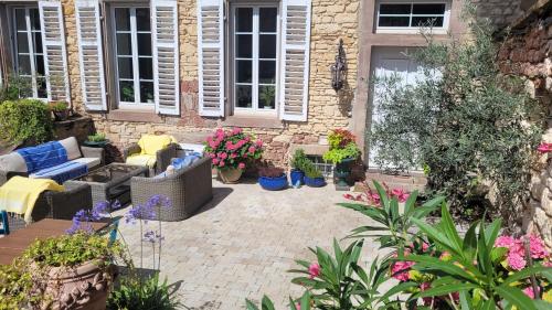 a patio with furniture and flowers in front of a building at Chambres d'Hôtes du Marché aux Grains in Bouxwiller